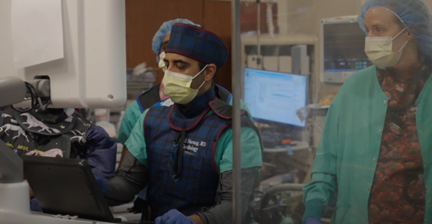 Physician and team in leads, performing robotic surgery