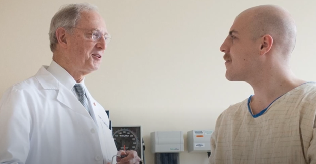 Physician in white lab coat speaking with patient in a hospital gown