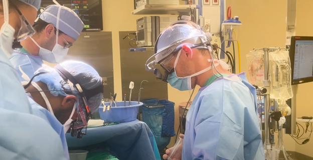 Four physicians performing surgery on a patient in the operating room