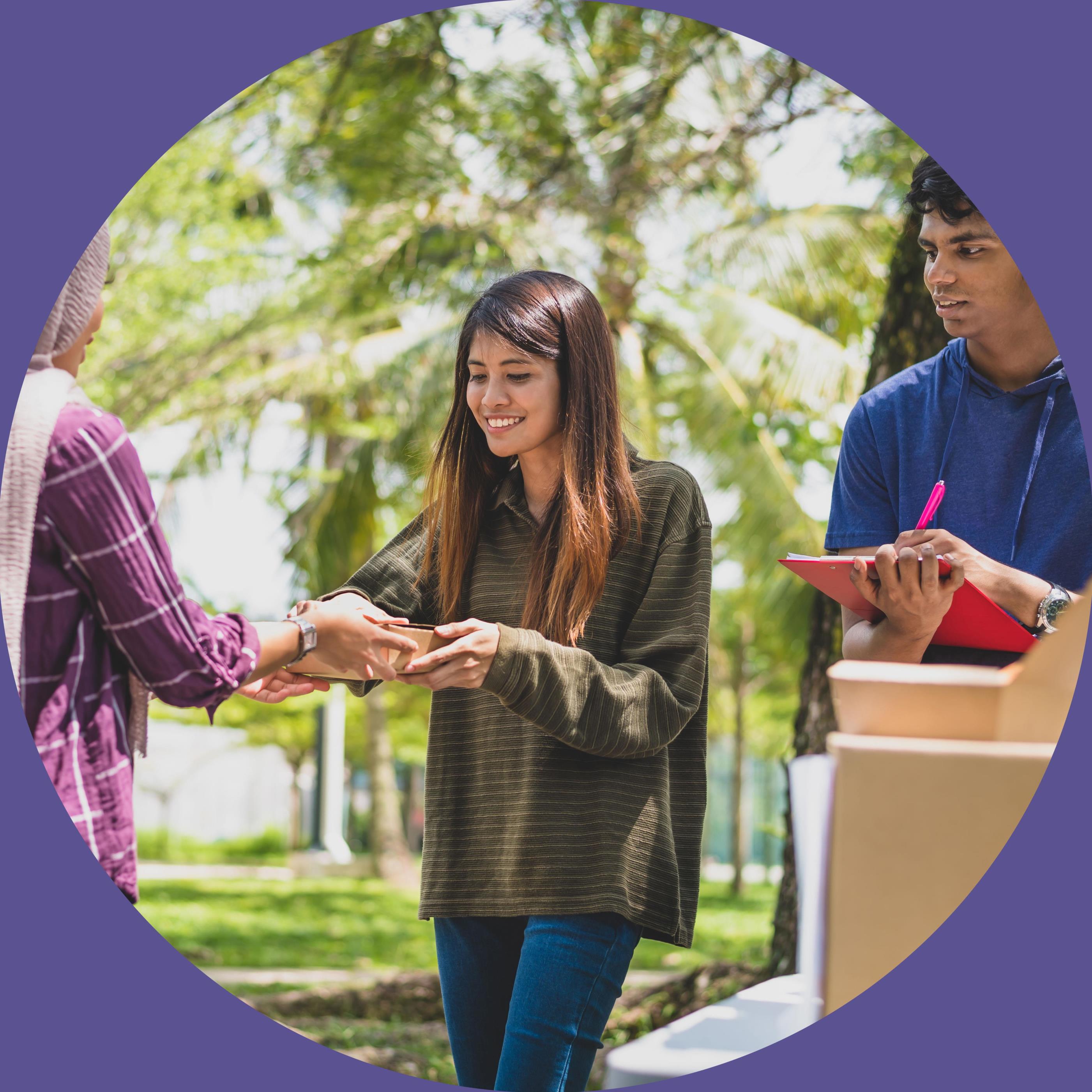 Male and Female volunteer at a food bank handing out food.