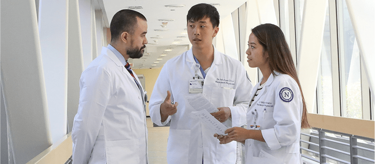Student workers wearing lab coats talking in a hallway
