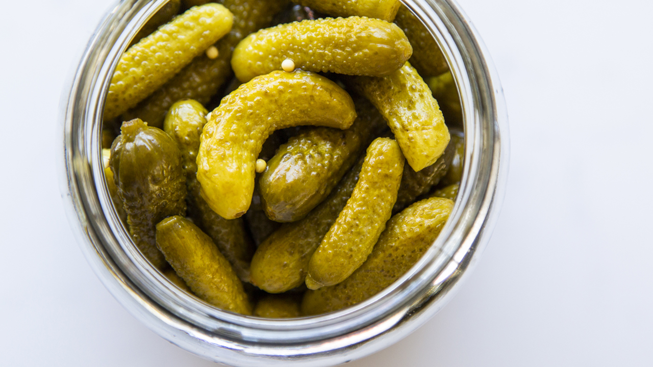 A jar of pickled baby cucumbers.