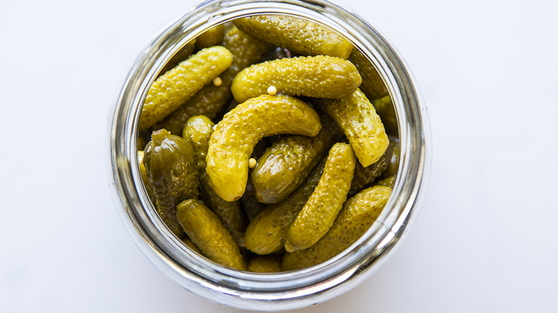 A jar of pickled baby cucumbers.