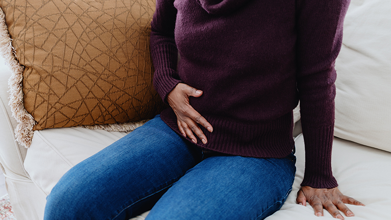 Person holding the lower right side of their stomach.