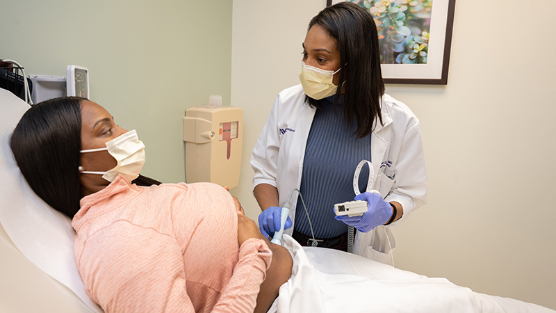 Arjeme Denise Cavens, MD, who is Black, examines a Black OB-GYN patient.