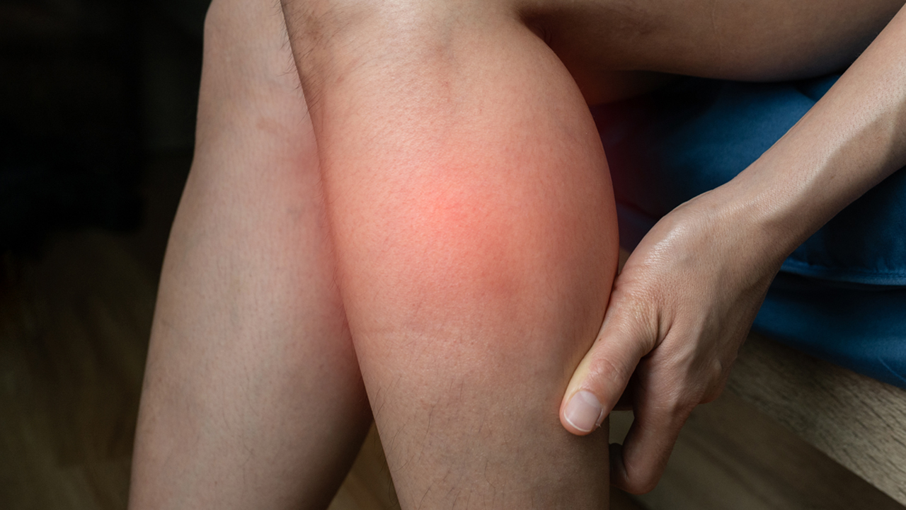 Person clutching their calf muscle in pain. 