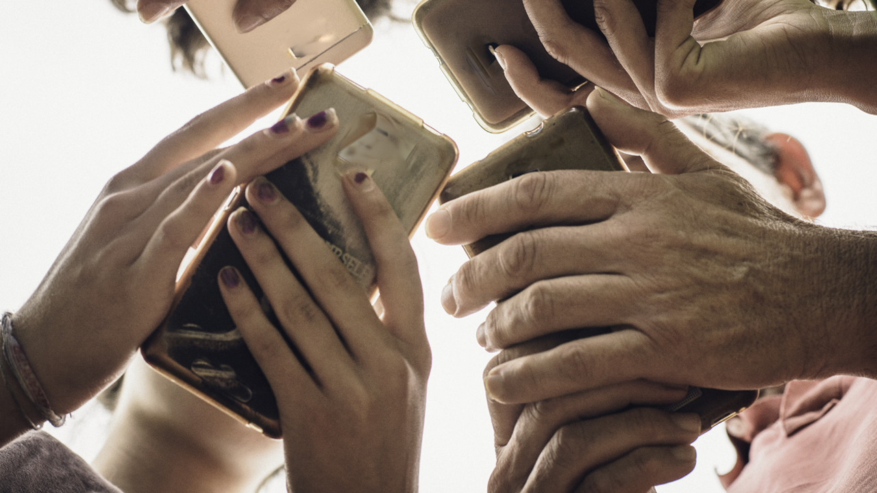 Low angle view of people grouped together using their smart phones. 