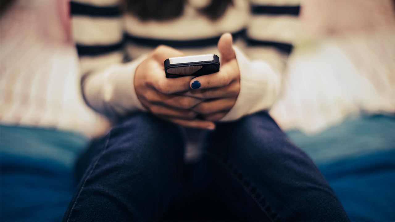Close up of teenage girl in a bedroom using a smartphone.