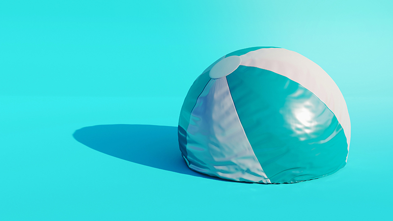 Blue and white beachball that is half deflated.