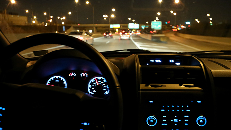 Interior view of a moving car on a dark highway at night. 