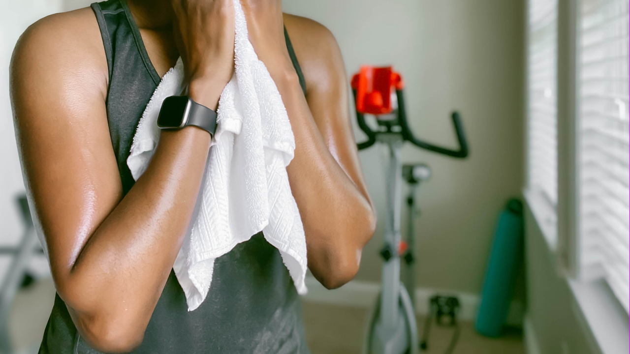 A sweaty person toweling off after a workout while wearing a smartwatch.