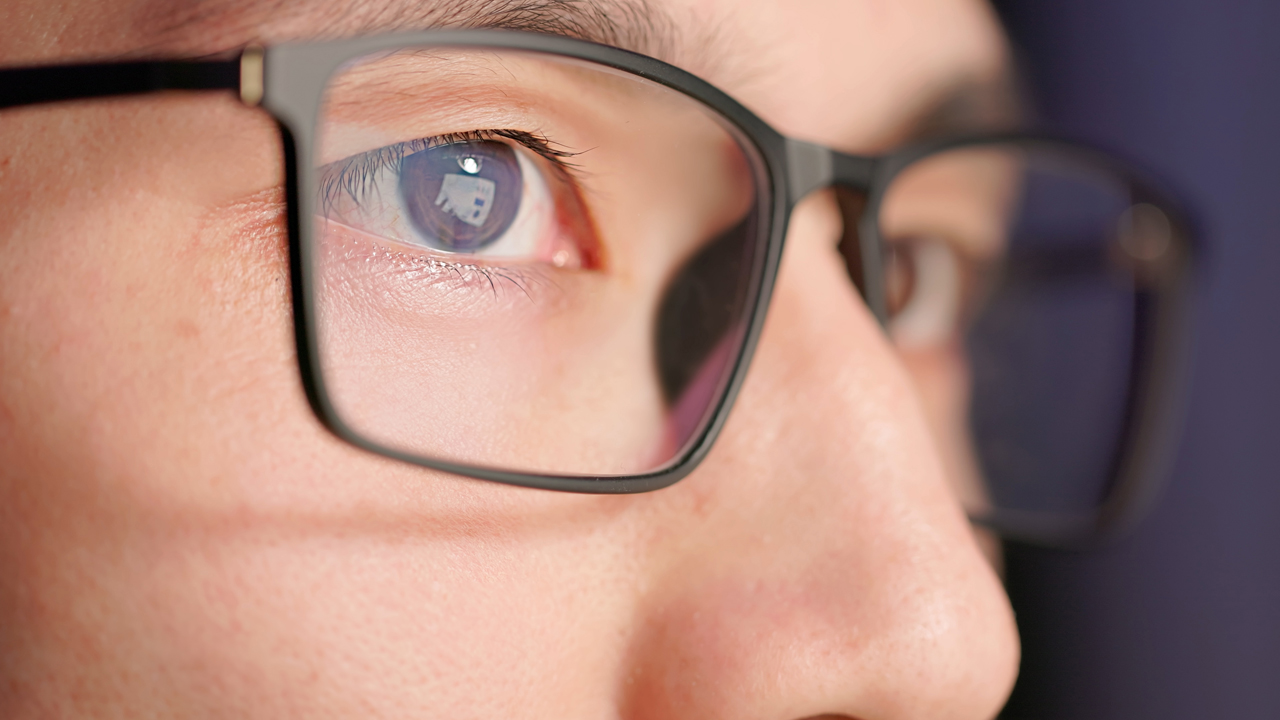 Close up of a person with short black hair wearing black glasses