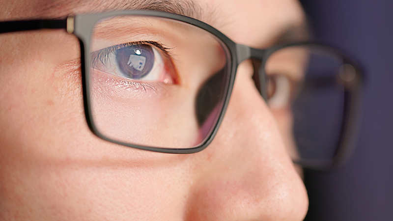 Close up of a person with short black hair wearing black glasses