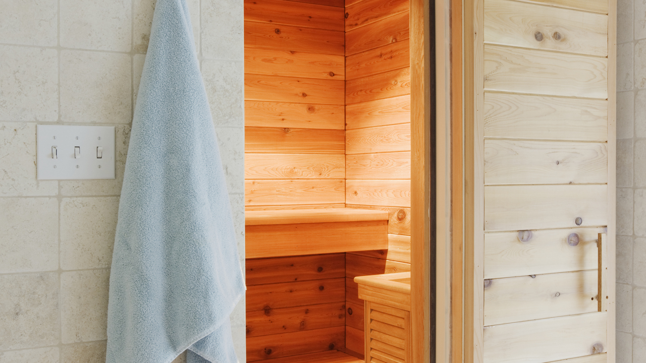 Infrared sauna with wooden panels with a blue towel outside the door.