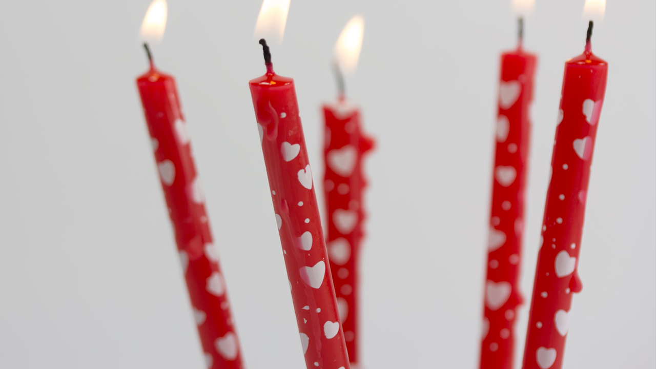 Lit red birthday candles with white hearts.
