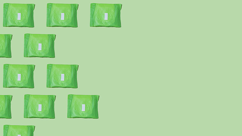 Sanitary napkins packed in green paper on a green background.