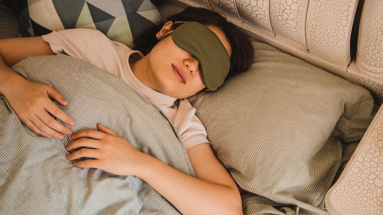 Person sleeping on their back on a pillow with eye mask