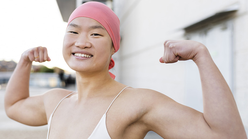 Happy woman wearing pink bandana showing biceps.