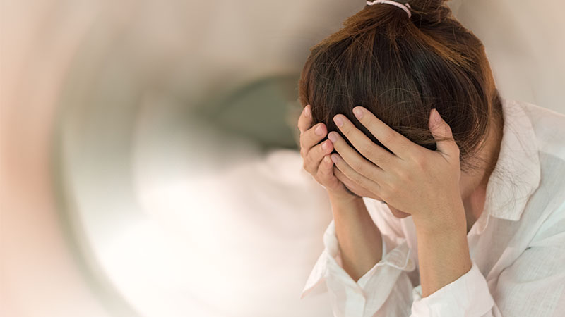 Picture of a woman with both hands on the side of her forehead 