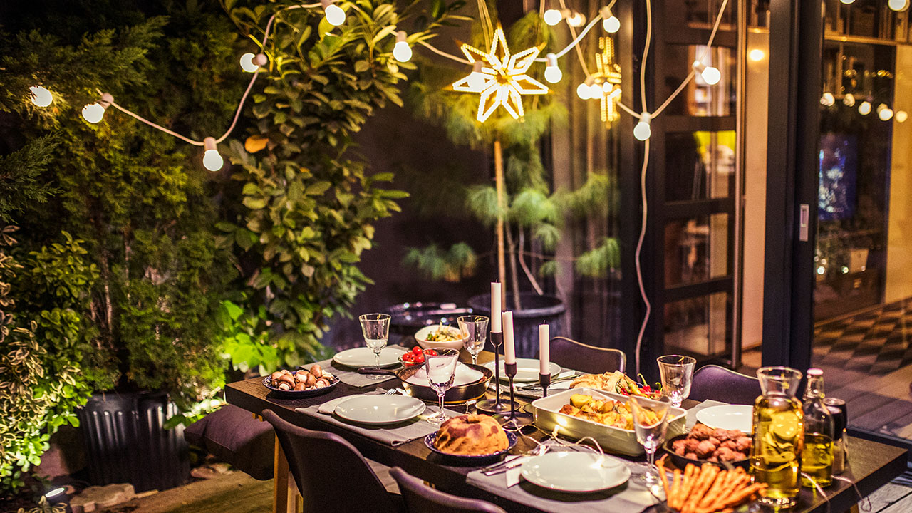 table set for dinner party in backyard with string lights