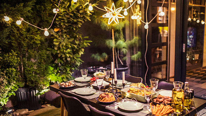 table set for dinner party in backyard with string lights
