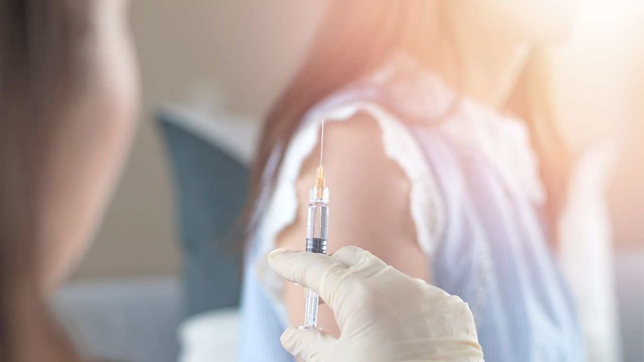 Woman having vaccination for HPV prevention with syringe by nurse or medical officer
