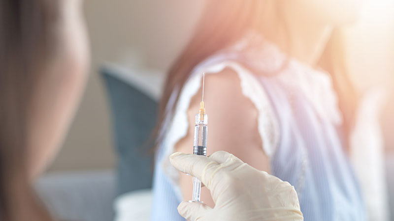 Woman having vaccination for HPV prevention with syringe by nurse or medical officer