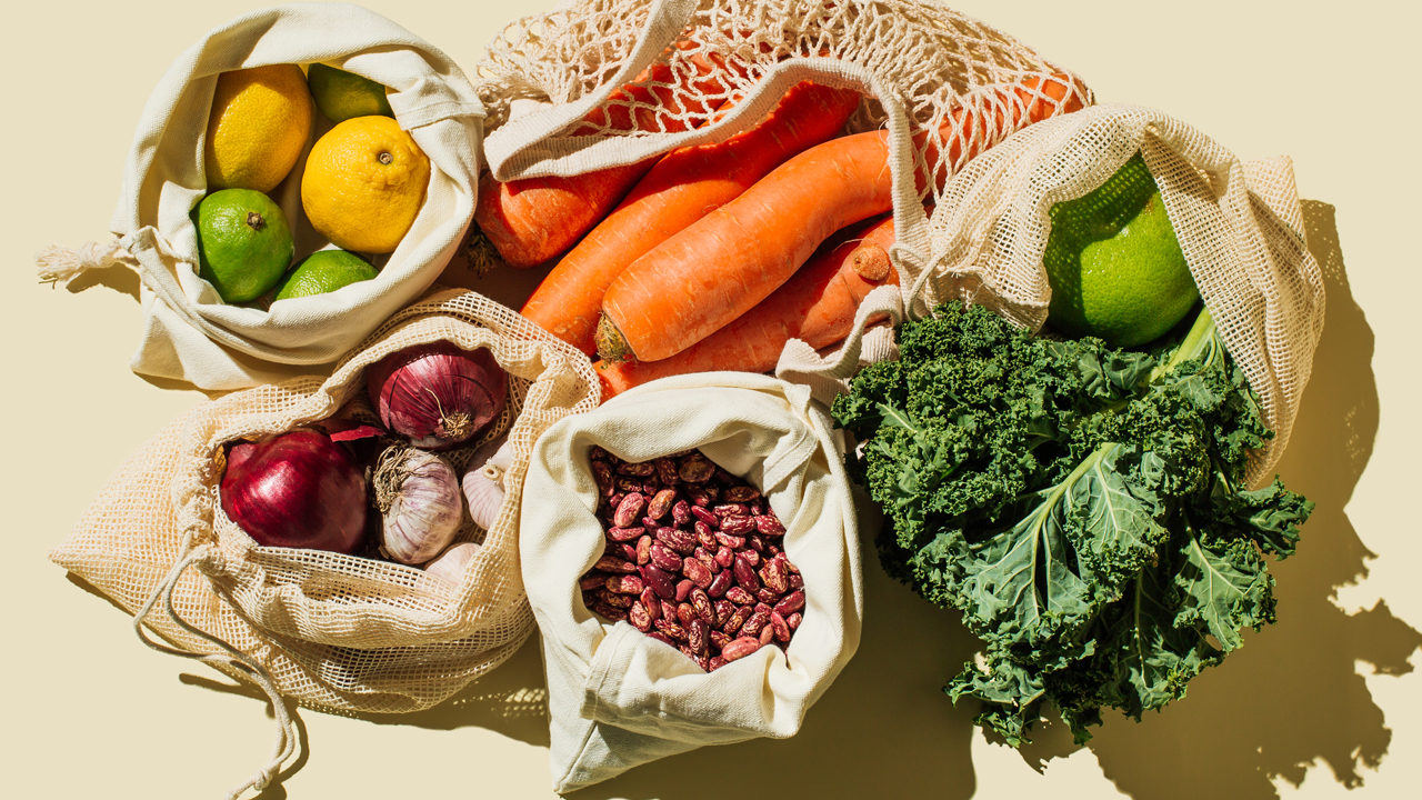 A variety of fresh fruits and vegetables in reusable bags.