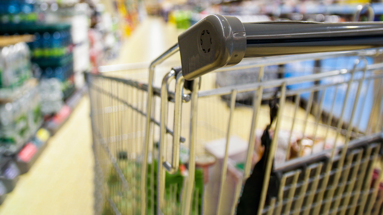 Close up of a shopping cart in the aisle of a grocery store. 