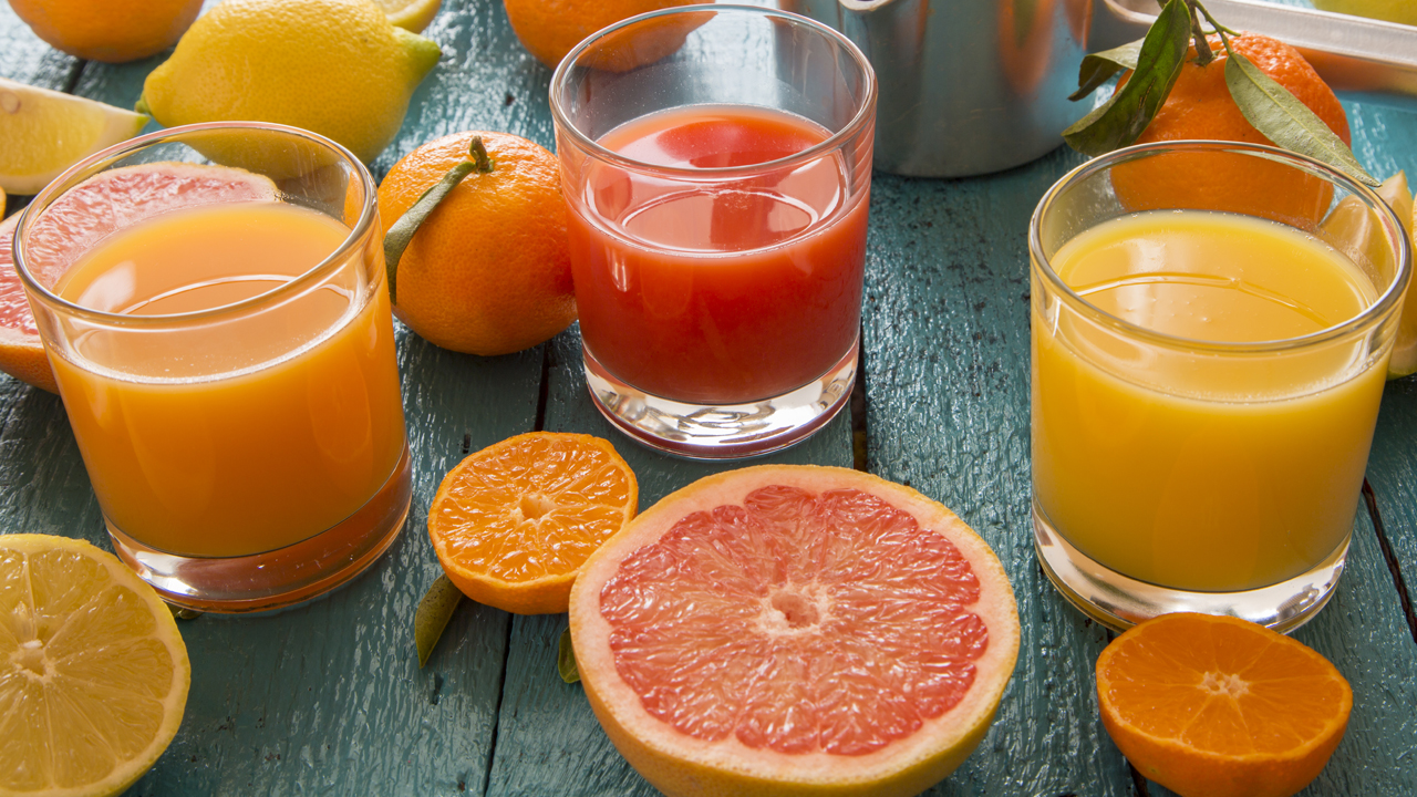 Glasses of orange and grapefruit juice on a blue wooden table. 