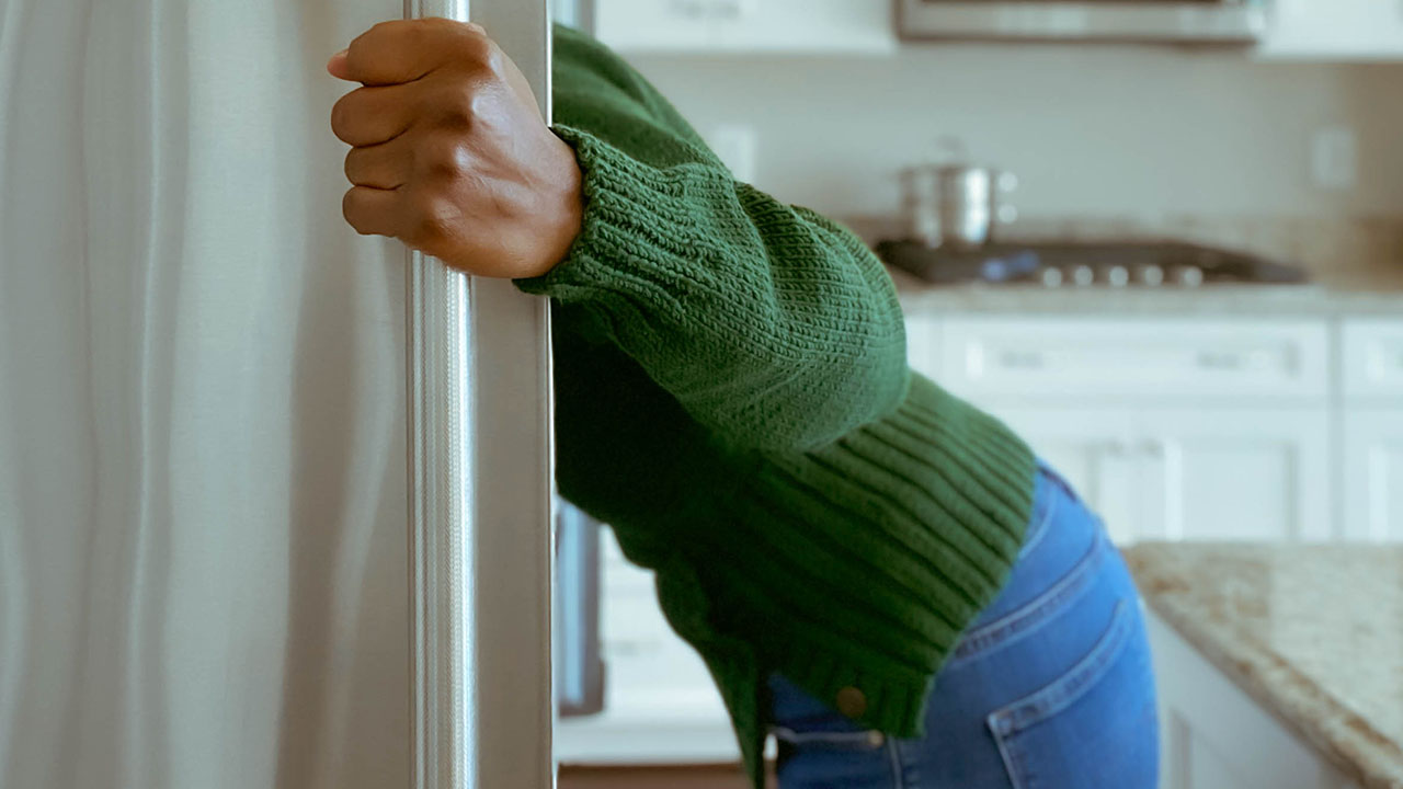 Person looking into a refrigerator looking for something to eat.