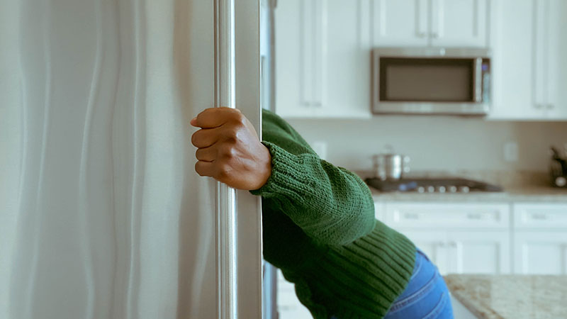 Person looking into a refrigerator looking for something to eat.
