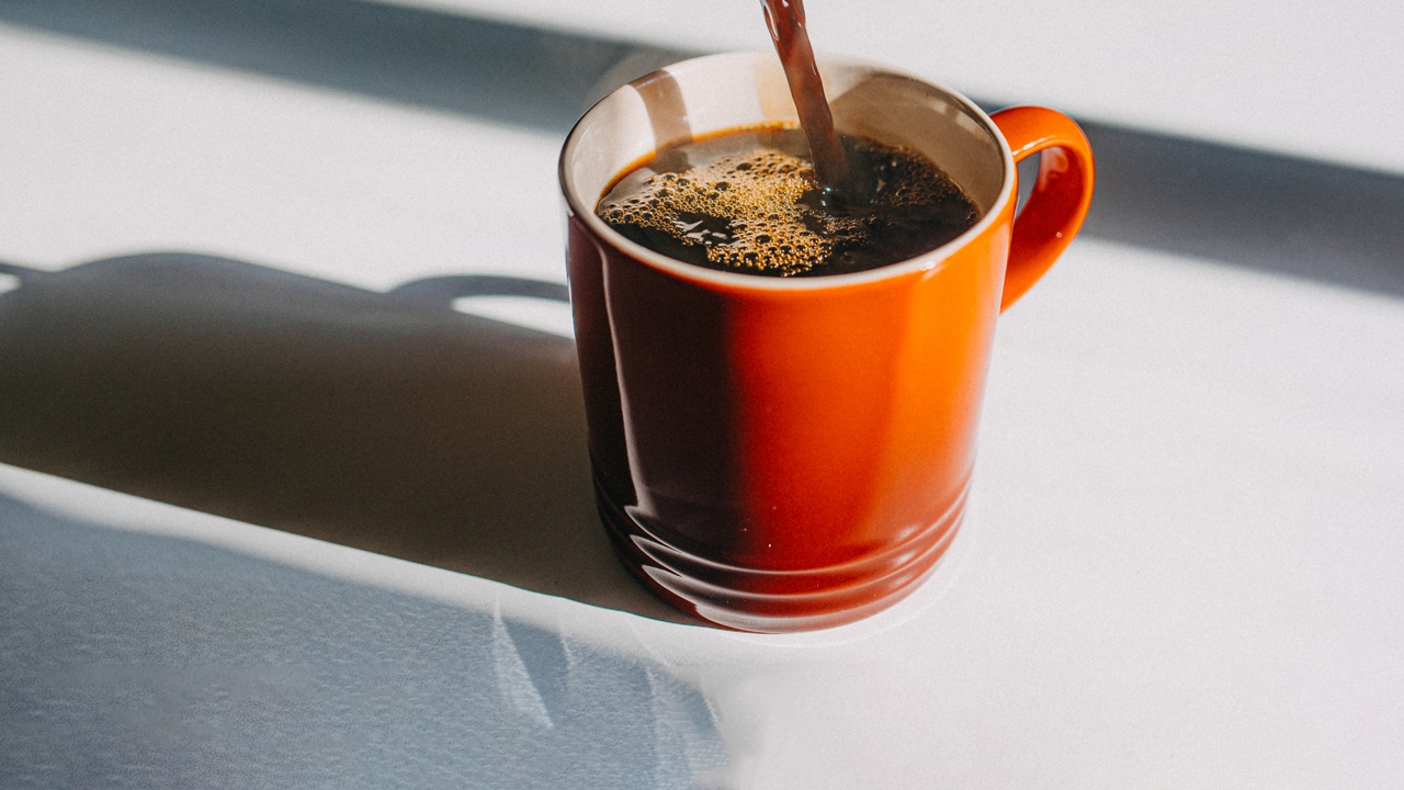 Coffee pouring into a red mug on a white table