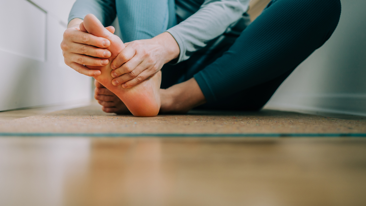 Person in yoga gear massaging the bottom of their foot.