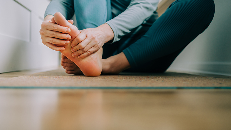 Person in yoga gear massaging the bottom of their foot.