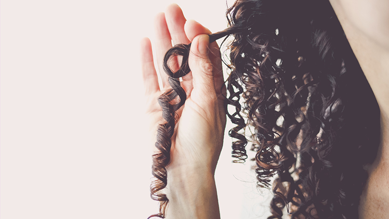 Close-up of a woman holding her tightly curled hair.