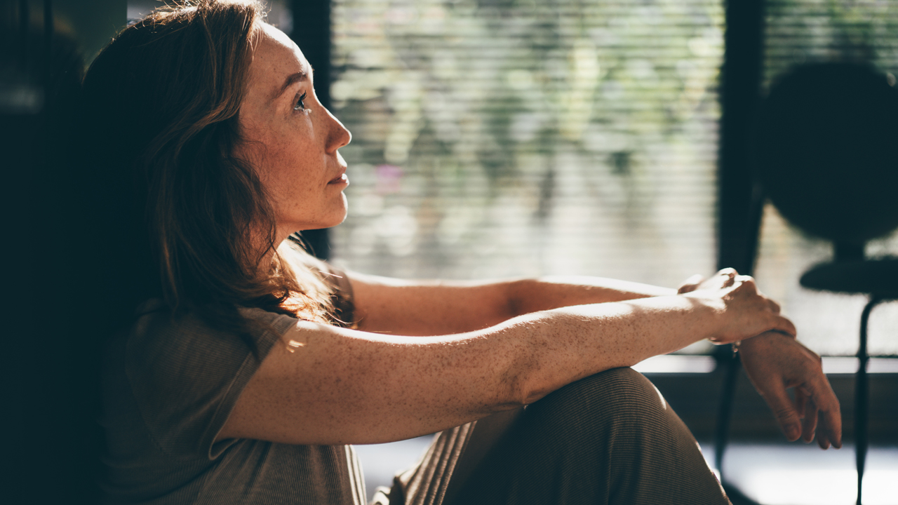 Contemplative woman sitting on the floor in a quiet moment. 