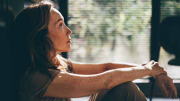 Contemplative woman sitting on the floor in a quiet moment. 
