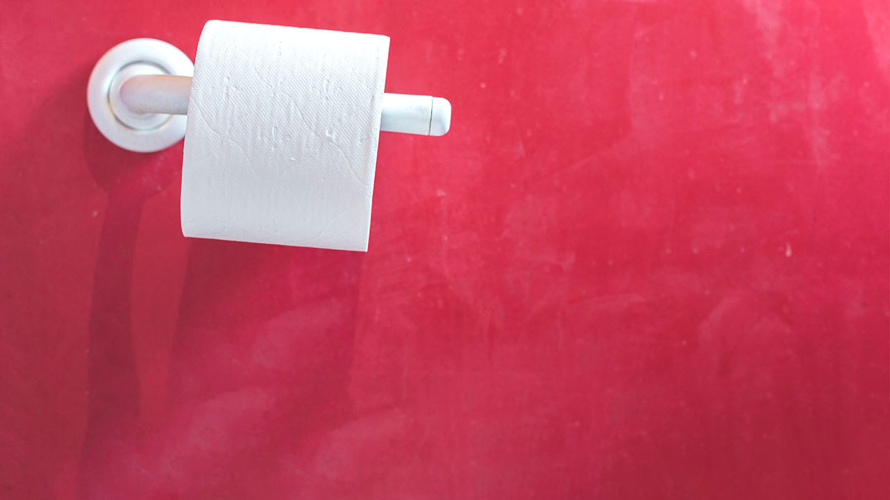 roll of toilet paper against red wall