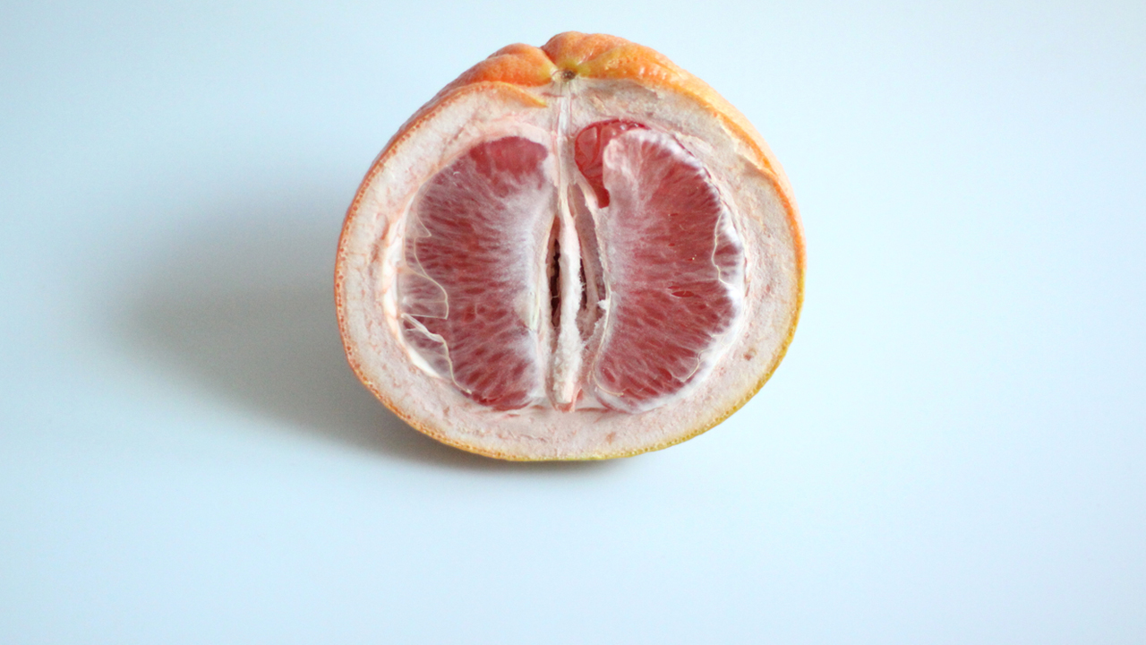 A semi-dry grapefruit half on a light blue background.