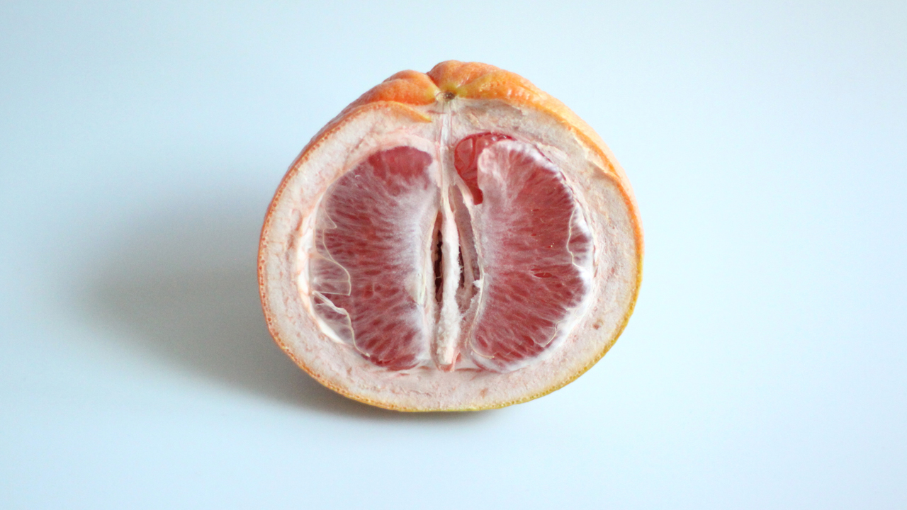 A semi-dry grapefruit half on a light blue background.