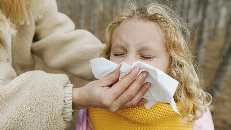Woman wiping a little girl’s nose with a tissue.