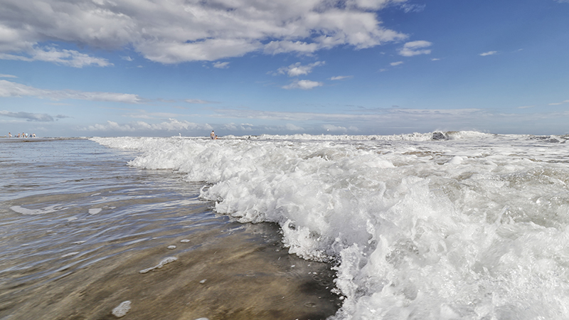 Waves crashing on a beach on a sunny day.