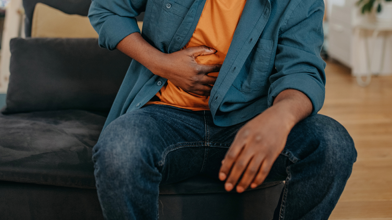Person seated with hand on abdomen as if in pain. 