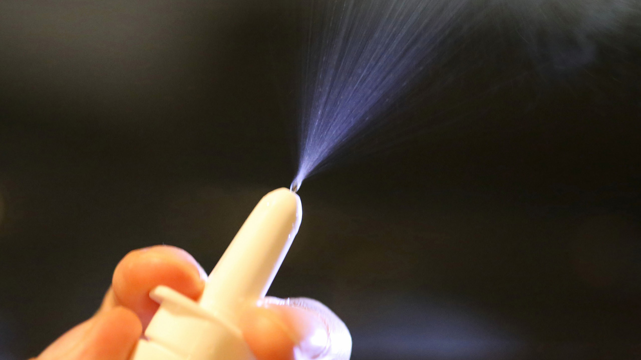 Hand holding naloxone spray.