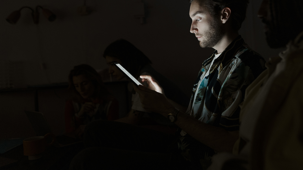 Young adult looking at smartphone in a dark room.