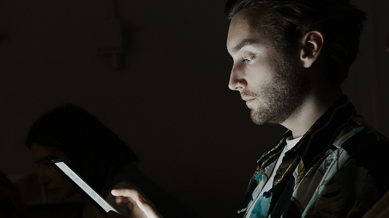 Young adult looking at smartphone in a dark room.