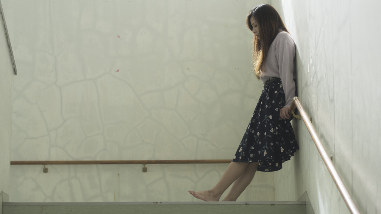 Winded person waiting on a stair landing.