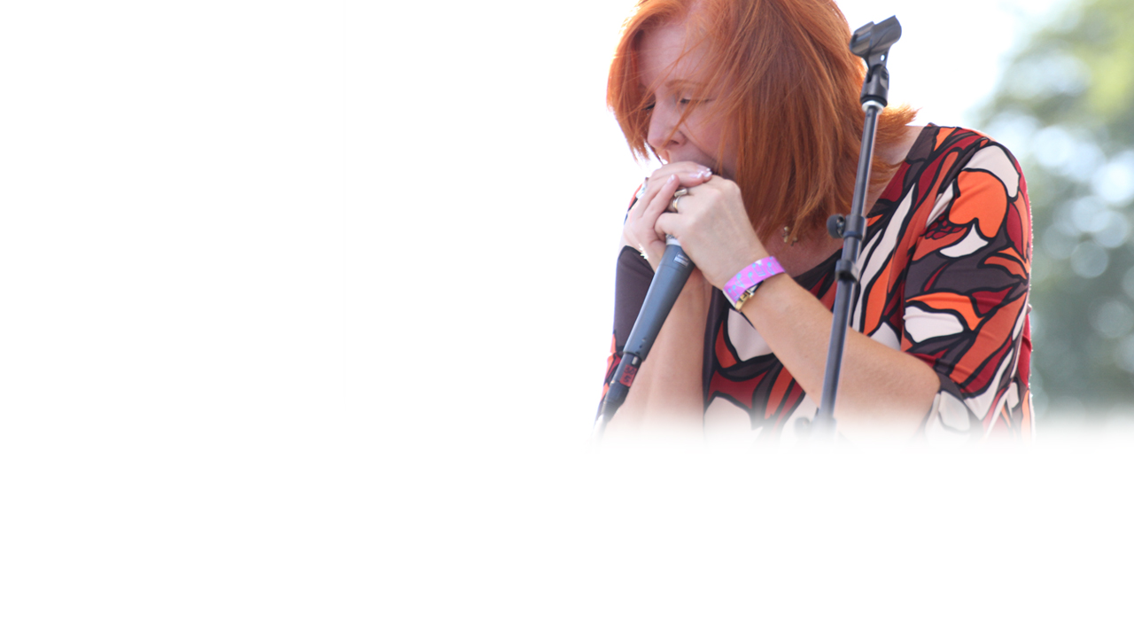 Geneva Red, jazz musician and blues singer, plays the harmonica on stage.