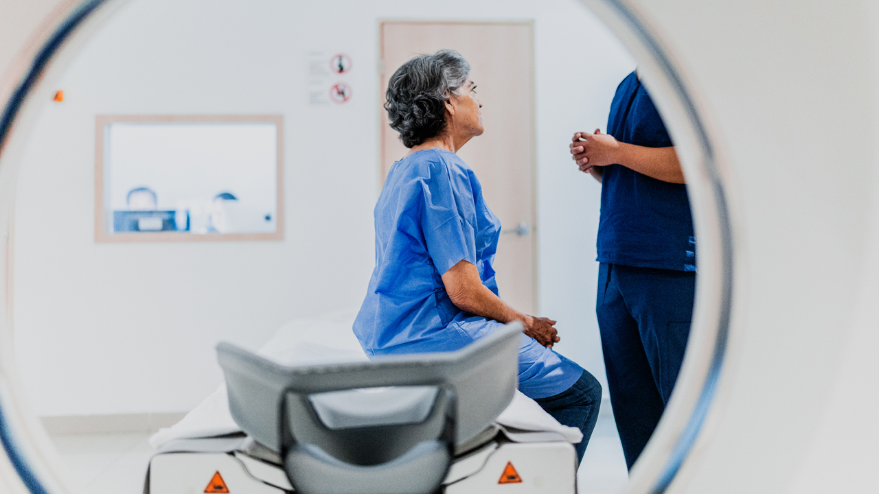 Patient talking to a clinician while seated on an MRI machine.